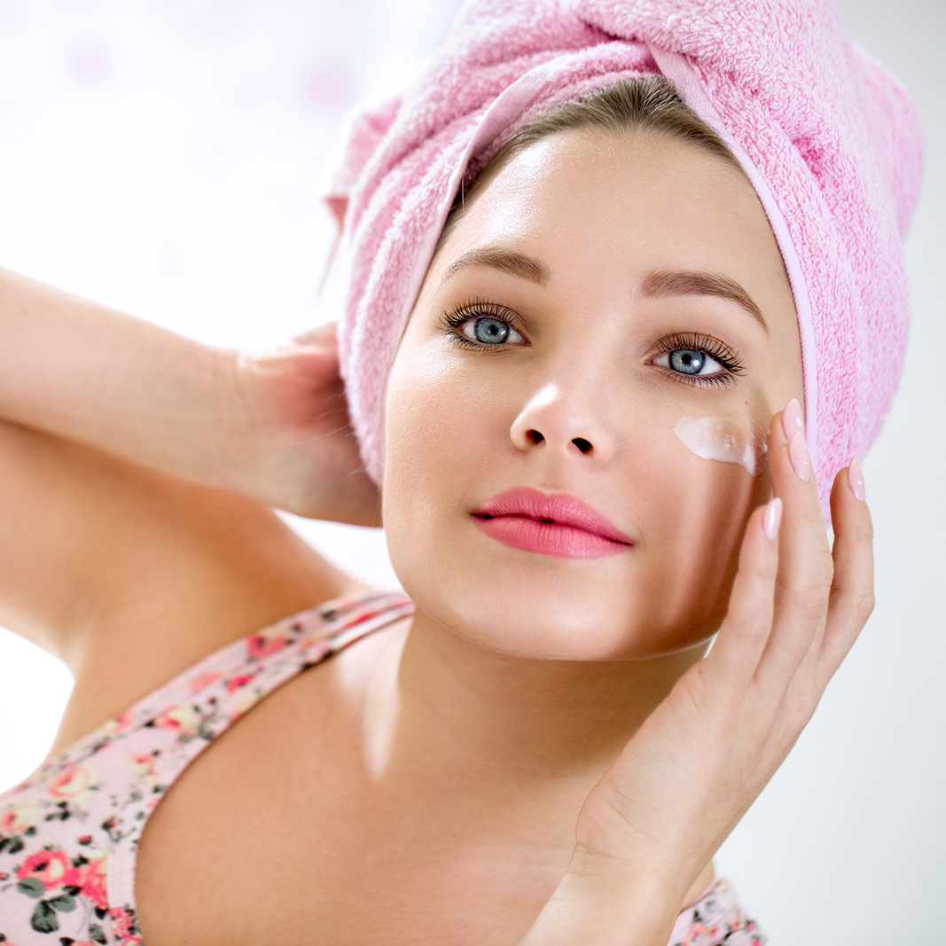 Young girl putting cream on her face